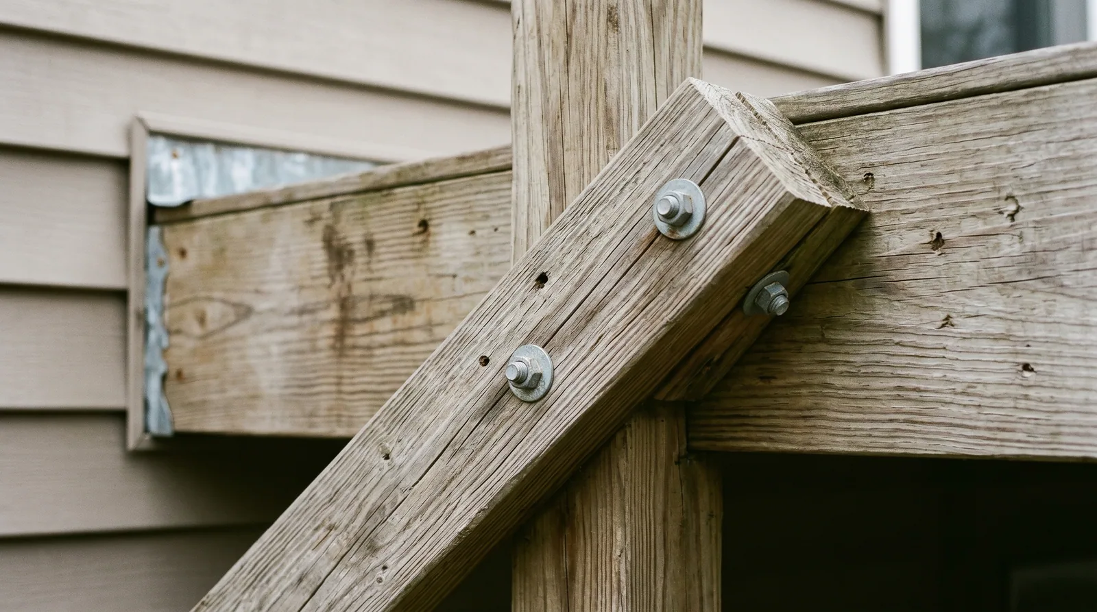 Close-up of deck wind bracing hardware showing a diagonal knee brace bolted to a post and beam, illustrating structural storm readiness for a deck in Raleigh, NC.