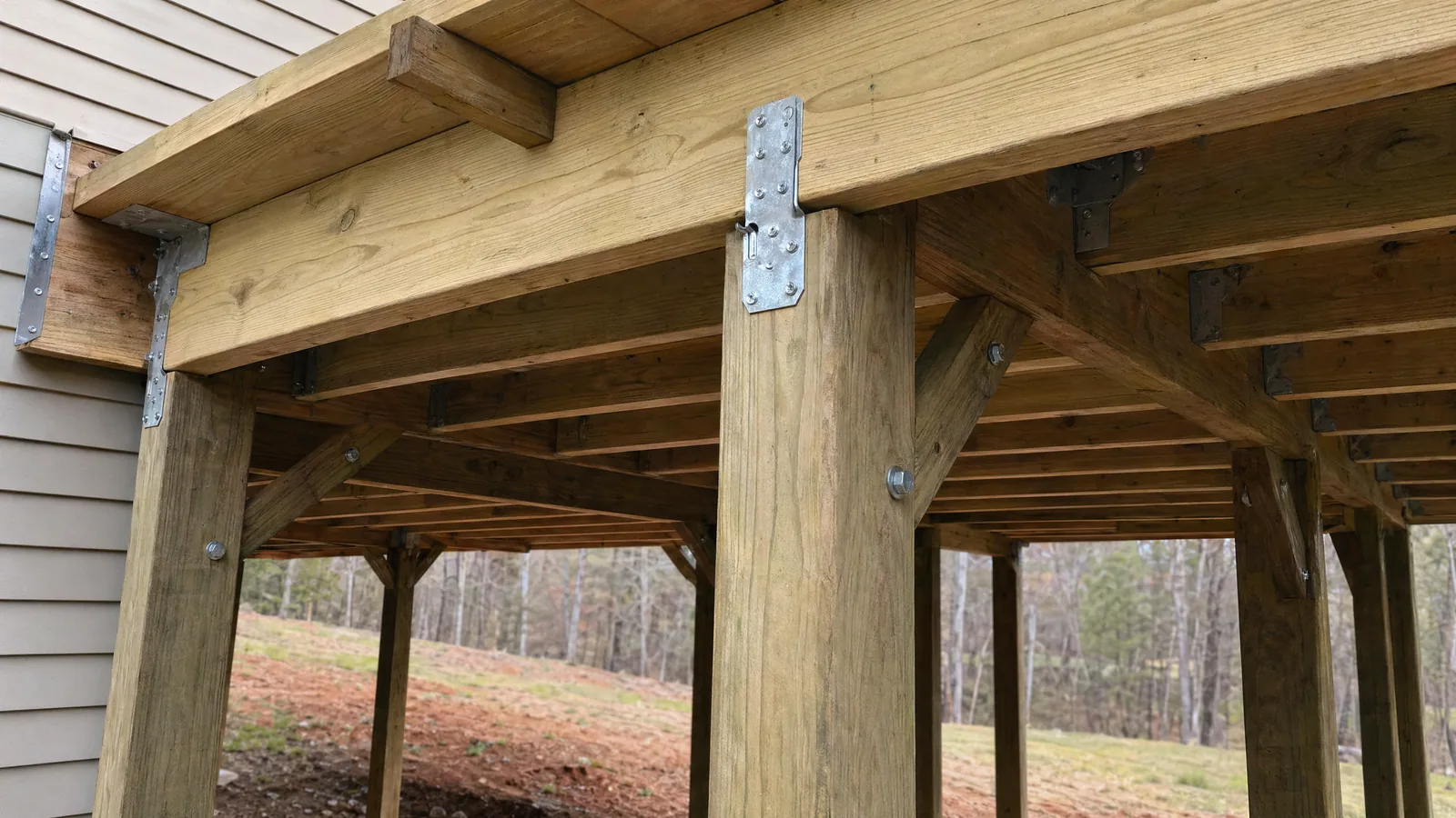 Close-up of elevated deck structural posts, beam connections, and diagonal knee bracing on a Raleigh area home