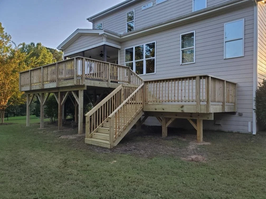 Newly framed two-story deck on a large home at golden hour