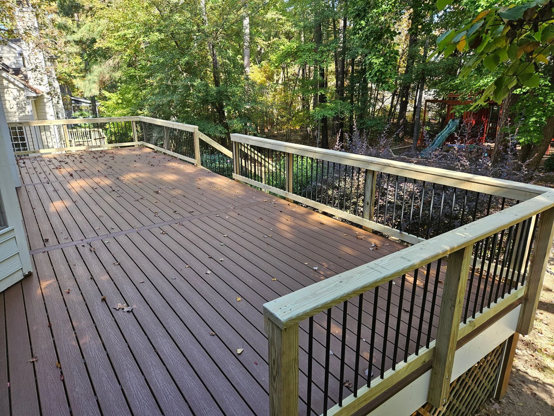 Composite deck off a sliding glass door with black aluminum balusters and lattice skirting